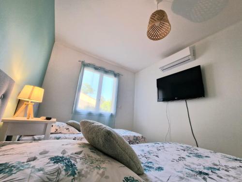 a bedroom with two beds and a flat screen tv at La perle de Dordogne in Le Bugue
