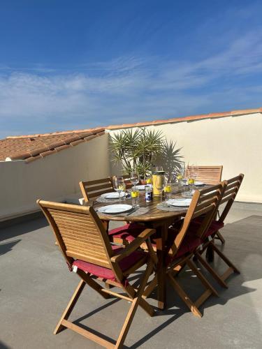 une table et des chaises en bois sur une terrasse dans l'établissement La Maison du Bonheur, au Cap d'Agde