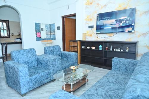 a living room with two blue chairs and a tv at Rudra Homes in Guwahati