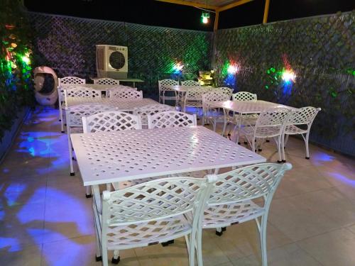 a row of white tables and chairs in a restaurant at Modest Rooms By Libra in Khizrābād