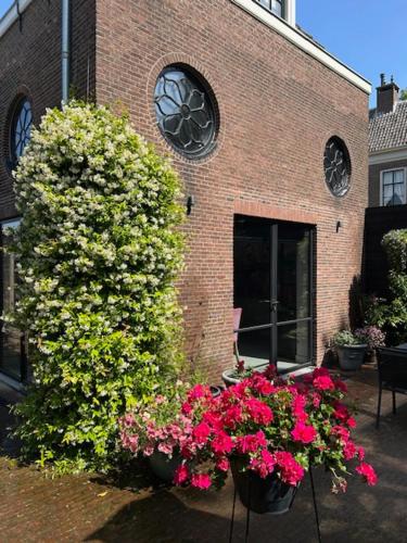 a brick building with flowers in front of it at Koetshuis aan het water 3 bedroom villa in Voorburg