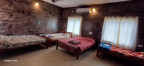 Cette chambre comprend 2 lits, une chaise et des fenêtres. dans l'établissement Manan Guest House, à Malpe