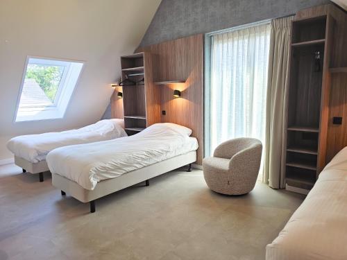Un dormitorio con dos camas y una silla y una ventana. en Luxe vakantievilla BG04, en Biggekerke
