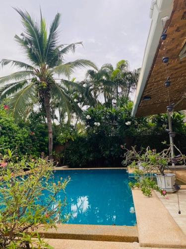 a swimming pool in front of a house with palm trees at Hidden Villa Oasis Private Pool 2km to BeachMall in Hua Hin