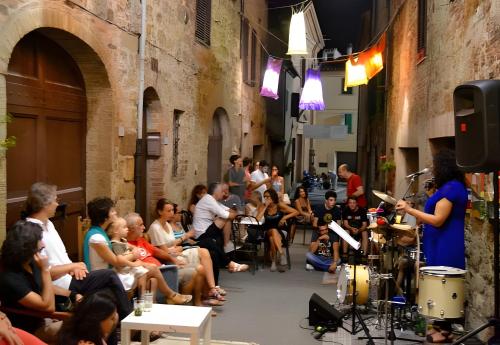 a crowd of people sitting in an alley with a woman playing drums at Agriturismo San Domenico-Il Roseto in Radicondoli