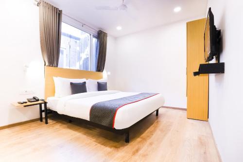 a hotel room with a bed and a television at Super Townhouse Prithvi Resort Near Phoenix Palassio in Lucknow