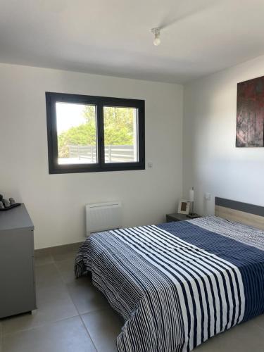 une chambre avec un lit avec une couverture rayée bleue et blanche dans l'établissement Maison 2 chambres avec Piscine sans vis à vis, à Villedaigne
