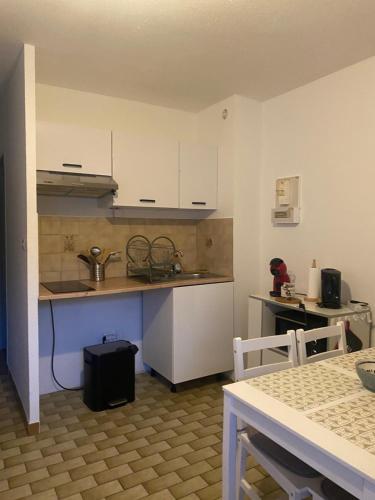 une petite cuisine avec des armoires blanches et une table dans l'établissement T2 ground floor near beach, à Valras-Plage