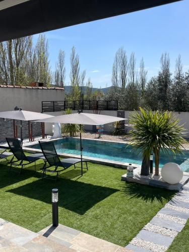 - une piscine avec 2 chaises et des parasols dans une cour dans l'établissement Maison 2 chambres avec Piscine sans vis à vis, à Villedaigne