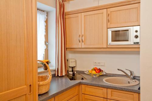 a kitchen with a sink and a microwave at Hotel Landhaus Feldmeier ***S in Oberammergau