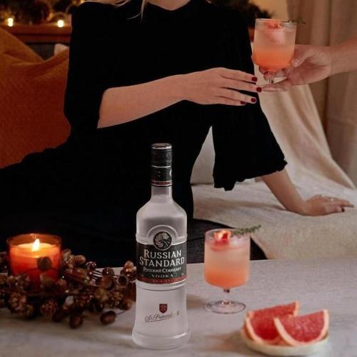 a woman is standing next to a bottle of gin at 4 Seasons Suites Paradise Athens Airport 2 in Markopoulo