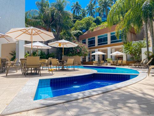 a swimming pool with tables and chairs and umbrellas at Portobello Ondina Praia in Salvador