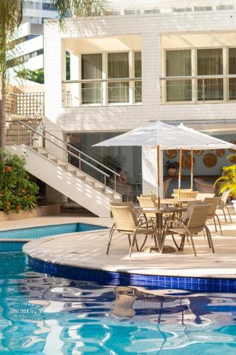 a patio with chairs and an umbrella next to a pool at Portobello Ondina Praia in Salvador