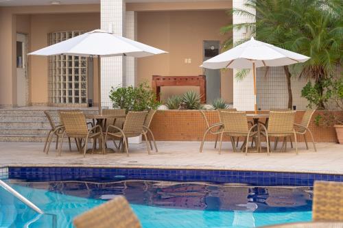 a patio with chairs and tables and umbrellas next to a pool at Portobello Ondina Praia in Salvador