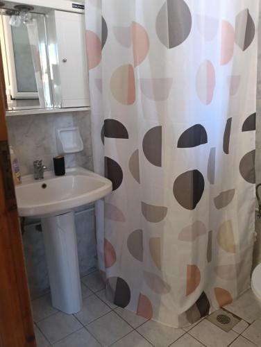 a bathroom with a sink and a shower curtain at ΤΑ ΩΡΑΙΑ ΤΗΣ ΑΘΗΝΑς in Skala Mistegnon
