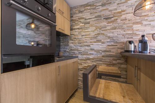 a kitchen with wooden cabinets and a brick wall at Les Chalets Autrichiens - Megève in Megève