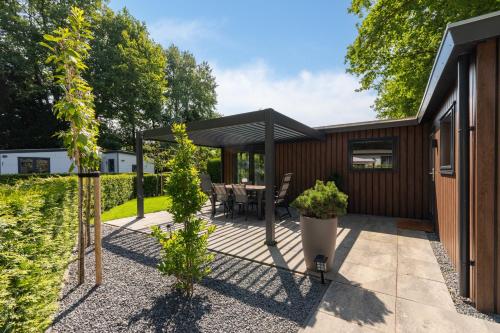 a patio with a table and a black umbrella at Bosrijk Austerpark chalet 29 in Putten