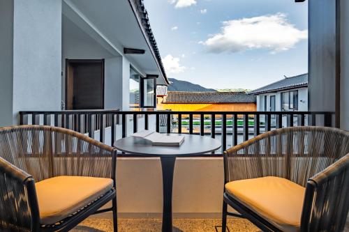 a balcony with a table and two chairs at 大理沙溪云喜七月精品客栈 Shaxi Ancient Town Yunxi Qiyue Guesthouse in Jianchuan