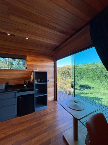 a kitchen with a table and a large window at Refúgio de Altitude in Urupema