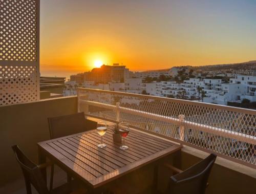 a table with two glasses on a balcony with the sunset at Ocean Sand holidays house in Adeje