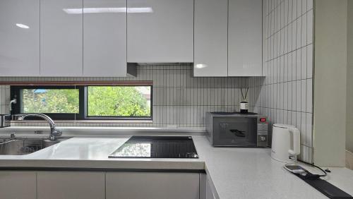 a kitchen with white cabinets and a sink and a microwave at Yeon Stay Miryang in Miryang