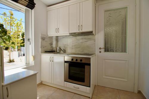 a kitchen with white cabinets and a stove and a window at Archontariki Luxury suites collection in Lakithra village in Lakithra