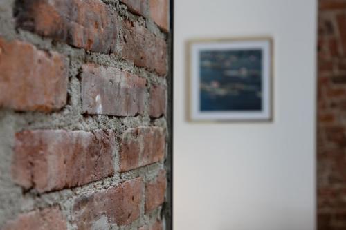 a brick wall with a framed picture next to a door at Polpo Apartments B&B in Łódź