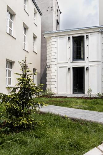 a building with white doors and a tree in the grass at Polpo Apartments B&B in Łódź