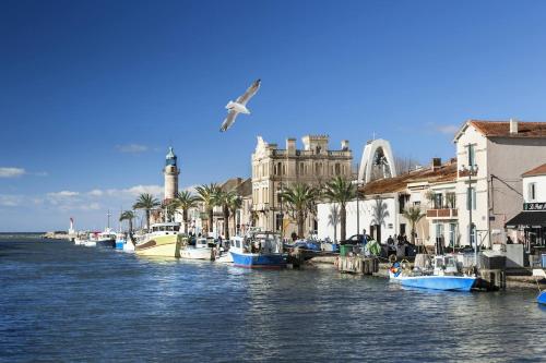un groupe de bateaux amarrés sur l'eau à côté de bâtiments dans l'établissement L'Escale Port-Camargue Grau du Roi, au Grau-du-Roi