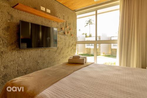 ein Schlafzimmer mit einem Bett und einem Fernseher an der Wand in der Unterkunft Casa Anamá em condomínio Naluum H9 by Qavi in Passo de Camarajibe