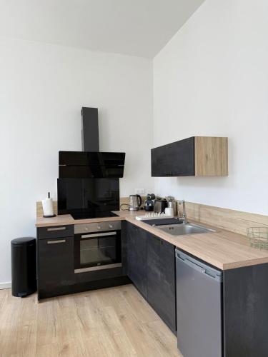 une cuisine avec des armoires noires et blanches et un évier dans l'établissement Appartement proche mer, à Royan