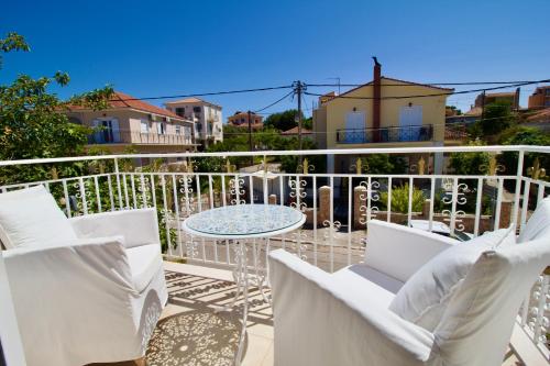 a patio with white chairs and a table on a balcony at Archontariki Luxury suites collection in Lakithra village in Lakithra