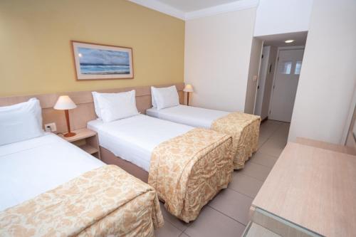 a hotel room with three beds and a table at Portobello Ondina Praia in Salvador