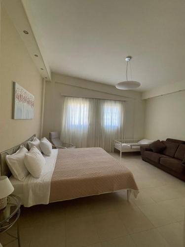a bedroom with a large bed and a couch at Nostrana Village Apartments in Koskinou