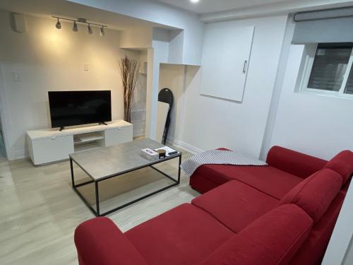 a living room with a red couch and a tv at Executive Apartment - 2BDR Parking Self-check in - Walkout basement Lower Unit in Mississauga