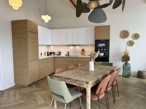 a kitchen and dining room with a wooden table and chairs at 765 - Maison moderne avec piscine privative. in Erquy