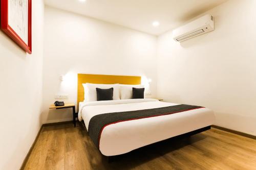 a bedroom with a large bed in a white room at Super Townhouse Prithvi Resort Near Phoenix Palassio in Lucknow