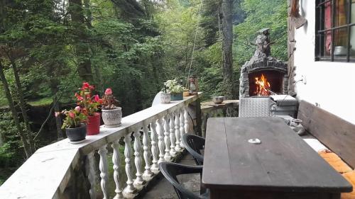 a table and a fireplace on a balcony with flowers at Villa Byala Luna - Guest House in Bistriza