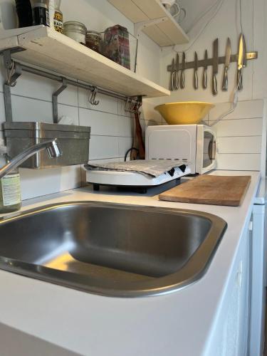 a kitchen with a sink and a microwave at Havsnära sommarhus på Älgö in Saltsjöbaden