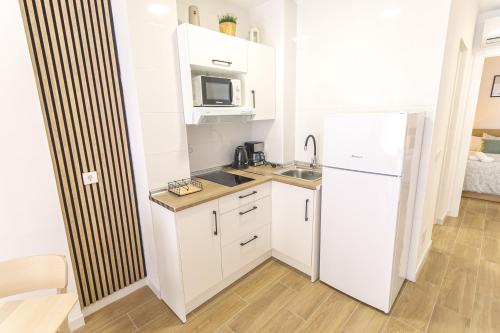 a kitchen with white cabinets and a refrigerator at Marimel Nerja Alojamientos in Nerja