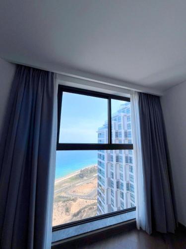 a large window with a view of a building at Apec Mandala Mũi Né Sun Sea Condotel in Mui Ne