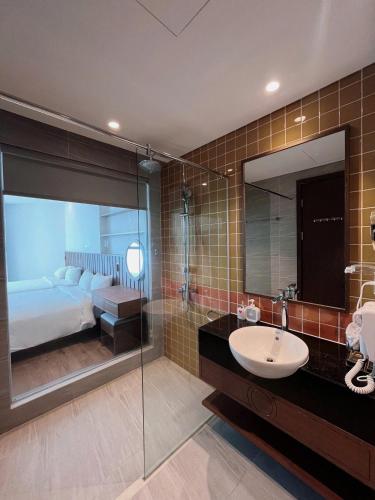 a bathroom with a sink and a bed and a mirror at Apec Mandala Mũi Né Sun Sea Condotel in Mui Ne