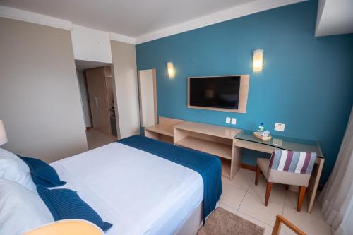 a bedroom with a bed and a desk and a tv at Portobello Ondina Praia in Salvador