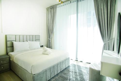 a white bed in a room with a large window at 1bhk brand new in JVC Binghatti Lavender in Dubai