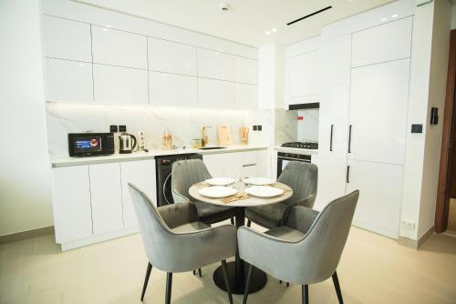 a white kitchen with a table and chairs at 1bhk brand new in JVC Binghatti Lavender in Dubai