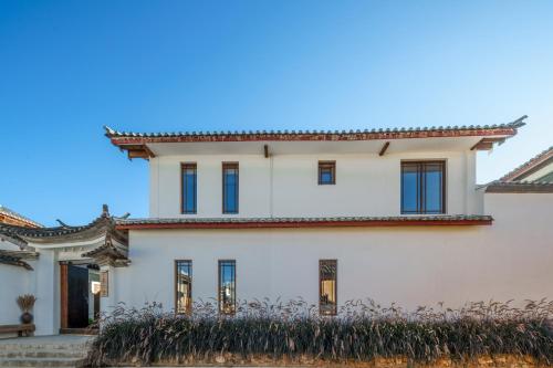 a white house with blue windows at 大理沙溪云喜七月精品客栈 Shaxi Ancient Town Yunxi Qiyue Guesthouse in Jianchuan
