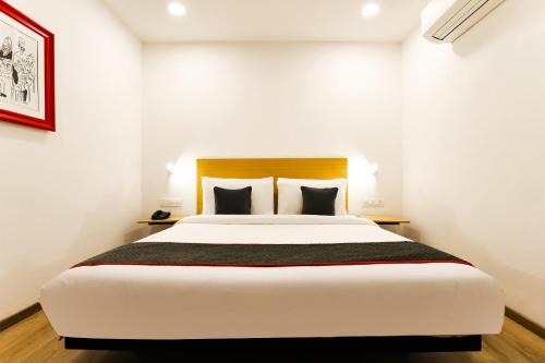 a bedroom with a large white bed with black pillows at Super Townhouse Prithvi Resort Near Phoenix Palassio in Lucknow