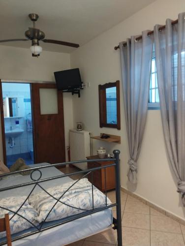 a bedroom with a bed and a tv and curtains at Trifyllianika Calm View in Trifilliánika