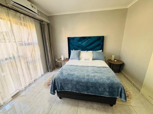 a bedroom with a large bed with a blue headboard at Dulelo Guest House Gaborone in Gaborone
