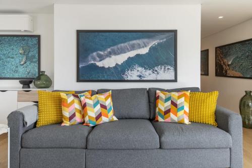 ein Wohnzimmer mit einem grauen Sofa und bunten Kissen in der Unterkunft Acqua Residence VIII by An Island Apart in Funchal